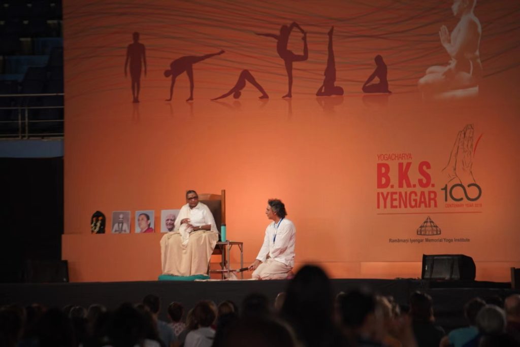 Photo taken in December 2018, at the celebration for BKS Iyengar's 100th birth anniversary, Geeta Iyengar inviting Zubin Zarthoshtimanesh on stage